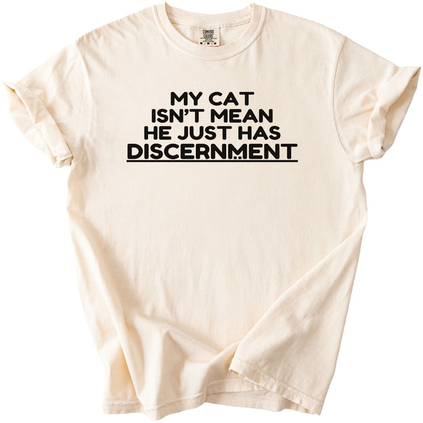 Cream t-shirt with black text "MY CAT ISN'T MEAN HE JUST HAS DISCERNMENT".