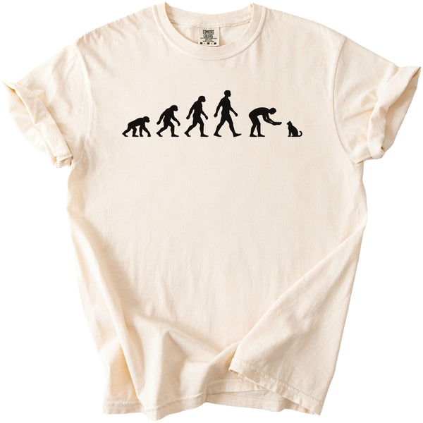 Cream t-shirt with black graphic of human evolution ending with a person feeding a cat.