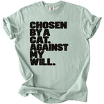 Light green t-shirt with black text "CHOSEN BY A CAT. AGAINST MY WILL."