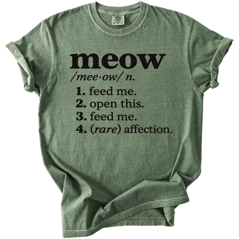 Green t-shirt with black text defining "meow" as "feed me, open this, feed me, (rare) affection."