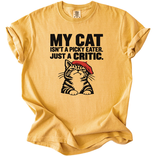 Yellow t-shirt with text "MY CAT ISN'T A PICKY EATER. JUST A CRITIC." and cat illustration.