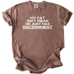 Brown t-shirt with white text "MY CAT ISN'T MEAN HE JUST HAS DISCERNMENT".