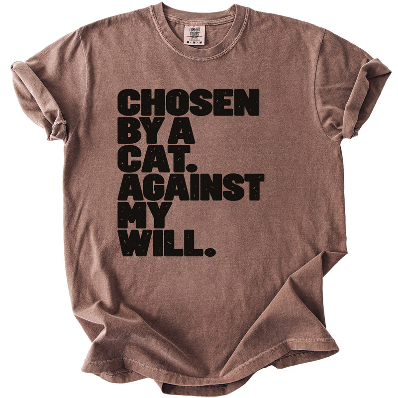 Brown t-shirt with black text reading "Chosen by a cat. Against my will."