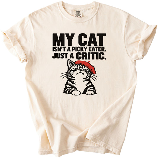 Cream t-shirt with text "MY CAT ISN'T A PICKY EATER. JUST A CRITIC." and cat illustration.